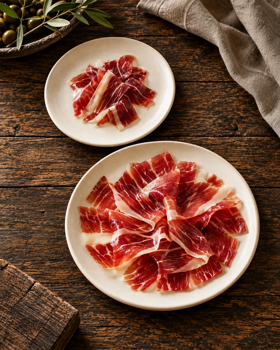 Due porzioni di prosciutto iberico affettato su piatti in ceramica